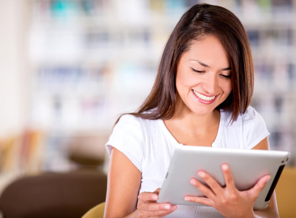 Woman reading at the library on an e-book reader