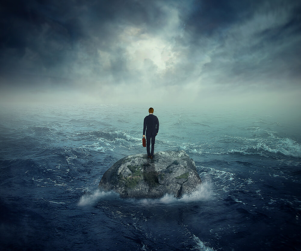 Failure crisis concept and lost business career education opportunity. Lonely young man on a rock cliff island surrounded by an ocean storm waves